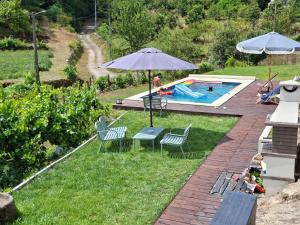 a backyard with a pool with chairs and an umbrella at Quinta da Peça Douro Wine Region Retreat, Private Pool Villa in Vila Real