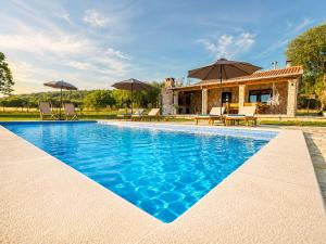 a pool with chairs and umbrellas in front of a house at Villa MaLea in Neum