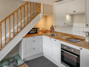 a kitchen with white cabinets and a staircase at The Cartshed - Uk50426 in Malton