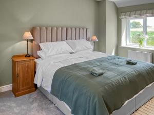 a bedroom with a large bed and a window at The Cartshed - Uk50426 in Malton +11 photos