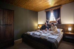 a family sitting on a bed with a baby at Resort Drevenice Terchova in Terchová +90 photos