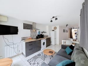 a living room with a couch and a kitchen at Urban Grey - Terrasse - Wifi in Châtellerault