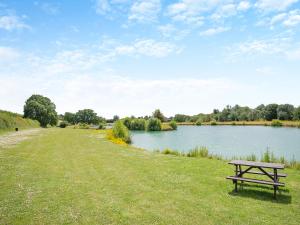 a picnic table sitting in the grass next to a lake at Greenhill Farmhouse in Bletchingdon
