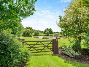 a wooden fence in a field with a river at Greenhill Farmhouse in Bletchingdon