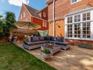a patio with a couch and a table and an umbrella at West Bay House in Westgate-on-Sea