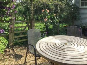 a wooden table with two chairs and a fence at Fig Tree Shepherds Hut in Bridport