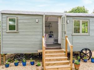 a gray tiny house with stairs leading to the door at Fig Tree Shepherds Hut in Bridport