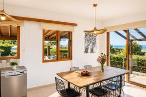 a kitchen with a wooden table and chairs and windows at Villa Argaka Heights in Argaka
