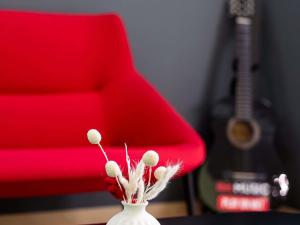 a red chair and a vase with flowers on a table at Ibis Győr in Győr