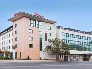 a large white building with a red sign on it at Ibis Győr in Győr