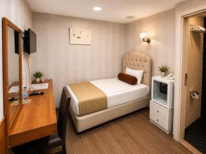 a bedroom with a bed and a desk and a television at Kuzen Otel in Istanbul +34 photos
