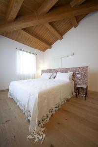 a bedroom with a large white bed with a wooden floor at Agriturismo Casacarella in Cesena