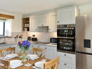 a kitchen with a table with chairs and a refrigerator at Deer Park Barn - Uk33323 in Reeth