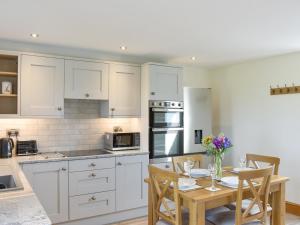 a kitchen with white cabinets and a table with chairs at Deer Park Barn - Uk33323 in Reeth