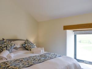 a bedroom with a white bed with a window at Deer Park Barn - Uk33323 in Reeth +17 photos