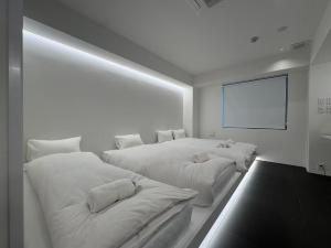 a white room with two beds and a screen at MARUKOUHOTEL 入船 inn in Tokyo