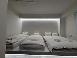 two beds in a room with white walls at MARUKOUHOTEL 入船 inn in Tokyo