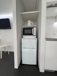 a kitchen with a microwave on top of a refrigerator at MARUKOUHOTEL 入船 inn in Tokyo +30 photos