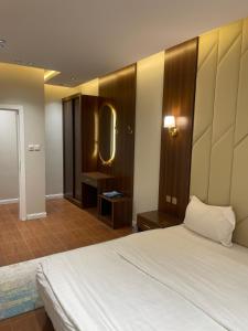 a bedroom with a white bed and a mirror at شقق jm احد رفيدة 2 in Ahad Rafidah