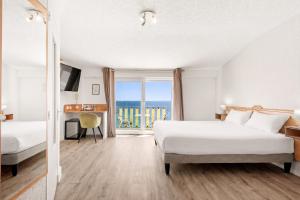 a hotel room with a bed and a view of the ocean at Le Beau Séjour in Saint-Raphaël