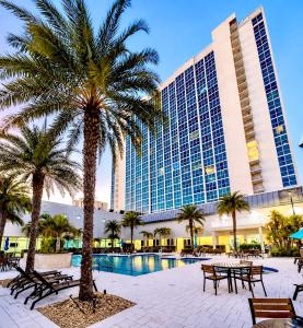 a resort with palm trees and tables and a building at Luxury Skyline Apartment- Resort-Style Pool , Gym & Game Room in Fort Myers