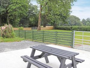 a wooden bench sitting on a sidewalk next to a fence at Gate House in Llangefni
