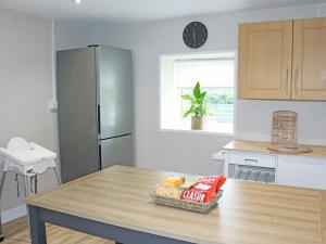 a kitchen with a table and a refrigerator at Gate House in Llangefni +13 photos