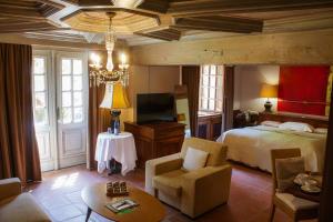 a bedroom with a bed and a tv and a couch at Hôtel le Moulin in Gundershoffen