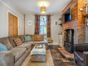 a living room with a couch and a fireplace at Melrose Cottage in Cromer +13 photos