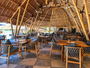 an empty restaurant with wooden tables and chairs at Komodo Resort in Sebayur