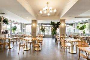 ein Restaurant mit Tischen, Stühlen und Fenstern in der Unterkunft Hotel EMI in Calderara di Reno