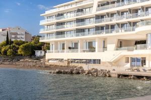 a large white building next to a body of water at Luxury Hotel Amabilis in Selce