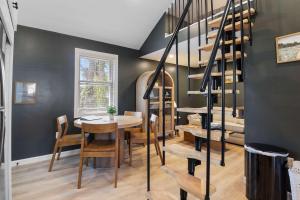a dining room with a table and a spiral staircase at Pelican Cliff Cottage - Tiny Home at Hampton Beach in Hampton