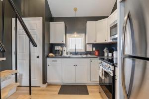 a kitchen with white cabinets and a stainless steel refrigerator at Pelican Cliff Cottage - Tiny Home at Hampton Beach in Hampton