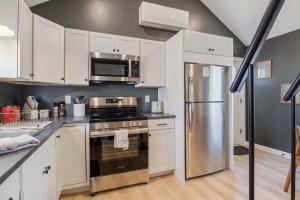 a kitchen with white cabinets and a stainless steel refrigerator at Pelican Cliff Cottage - Tiny Home at Hampton Beach in Hampton