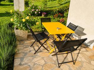 a yellow table and chairs on a stone patio at Les Lavandes de Vals in Vals-les-Bains