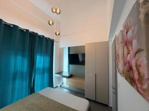 a bedroom with blue curtains and a bed and a tv at Viasol Suites Thassos in Skala Rachoniou
