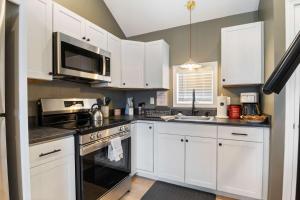 a kitchen with white cabinets and a stove top oven at Sandy Toes Cottage - Tiny Home at Hampton Beach in Hampton