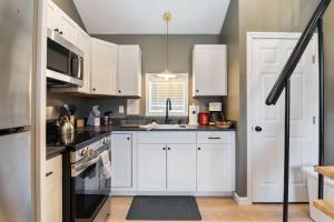 a kitchen with white cabinets and a stove top oven at Sandy Toes Cottage - Tiny Home at Hampton Beach in Hampton +23 photos