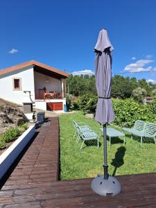 an umbrella on a deck with two benches and a house at Quinta da Peça Douro Wine Region Retreat, Private Pool Villa in Vila Real