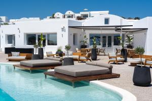 a swimming pool with lounge chairs and a house at Oikos Santorini Living Concept in Fira