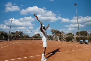 a man serving a tennis ball on a tennis court at Barceló Palmeraie Oasis Resort in Marrakesh