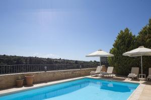 a swimming pool with two chairs and umbrellas at Ilys Home, a Country-chic Retreat with Pool & BBQ, By ThinkVilla in Margarítai +53 photos