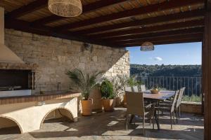 a patio with a table and chairs and a stone wall at Ilys Home, a Country-chic Retreat with Pool & BBQ, By ThinkVilla in Margarítai