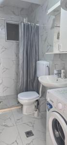 a white bathroom with a toilet and a sink at Taksim Apartman in Igalo