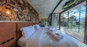 a bedroom with a large bed with a stone wall at Rancho Canto da Lua in Urubici