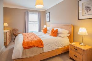 a bedroom with a bed with orange pillows and a window at Hudson House in Durham