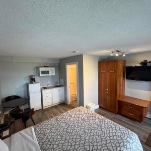a bedroom with a large bed and a kitchen at Motel Brise Marine in Shippagan