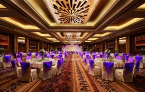 鄭州市にあるZhengzhou Yuehai Hotelの白いテーブルと紫色の椅子が備わる宴会場