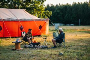 two men sitting around a fire in front of a tent at Jurtowisko in Wilcza Wólka